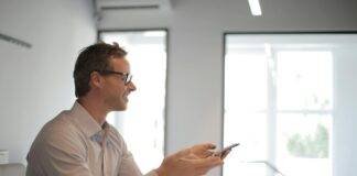 smiling adult businessman at table with gadgets holding presentation