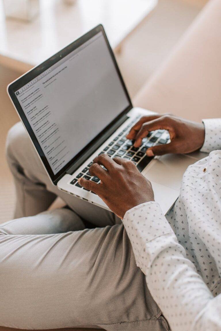 photograph of a person typing on a silver laptop