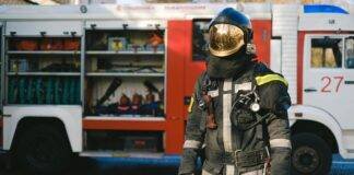 a firefighter in uniform standing near a fire truck