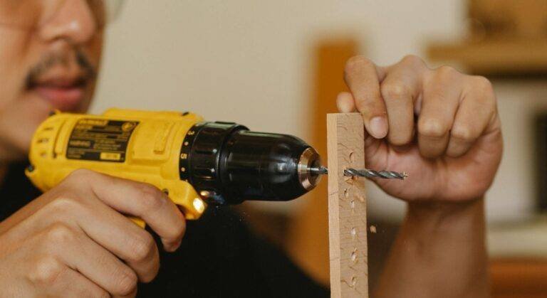 crop man drilling holes in wooden plank
