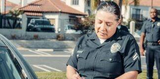a police officer standing beside a car while holding a clipboard