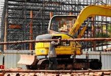 man carrying a wooden trunk and an excavator