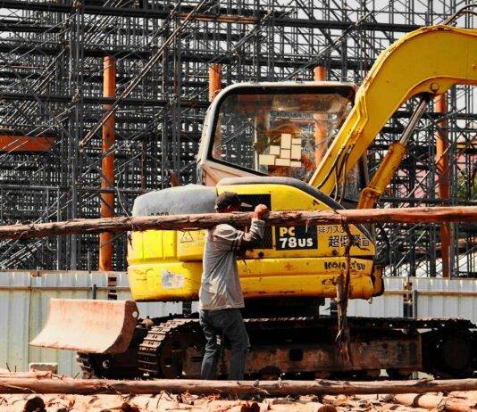 man carrying a wooden trunk and an excavator