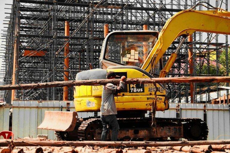 man carrying a wooden trunk and an excavator