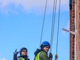 workers in climbing equipment on the building wall
