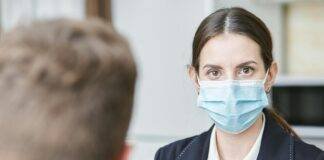 shallow focus of a woman in black suit wearing her face mask