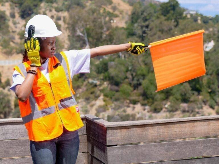handywoman holding an orange signaling flag