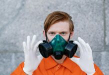 a person in orange top wearing a respirator mask and hand gloves