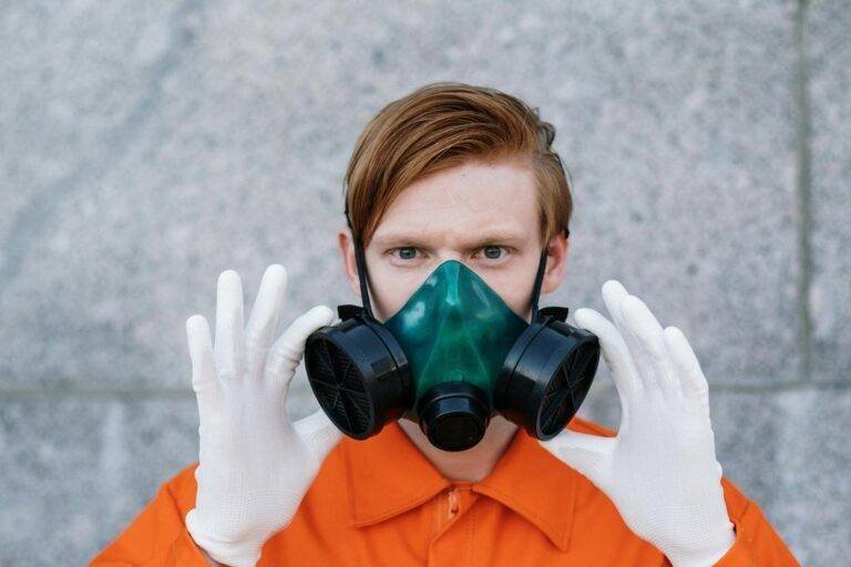 a person in orange top wearing a respirator mask and hand gloves