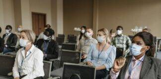 people wearing face mask sitting on the chair inside the conference room