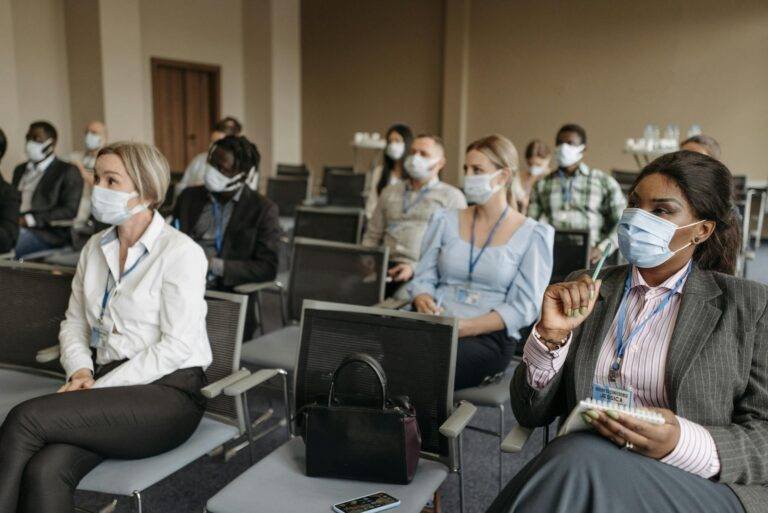 people wearing face mask sitting on the chair inside the conference room